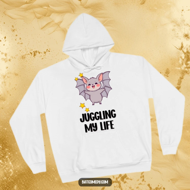 Funny hoodie featuring a bat joyfully juggling three small stars with its wings, creating a cozy and celestial atmosphere.